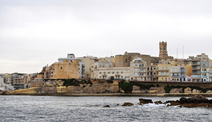 View from the water to the shore and the ancient buildings of  Buggiba,Malta. Buġibba is a zone within St. Paul's Bay in the Northern Region, Malta.