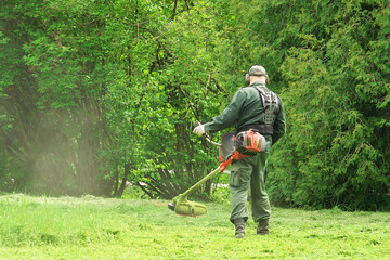 The man is mowing the lawn with a trimmer.