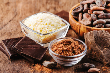 Various cocoa products set: beans, powder, butter, dark chocolate, grated cocoa on wooden table background