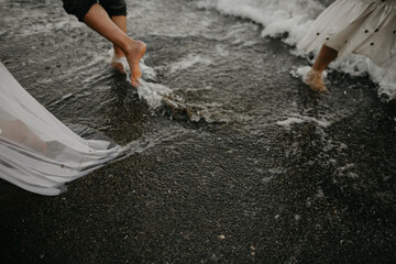 Obraz premium Close up of dark grey sand and human legs on the beach. Concept of a beach vacation.