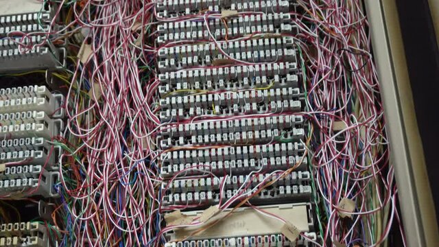 Inside a PBX telephone booth that has a number of connecting cables in many colors in the analog system.