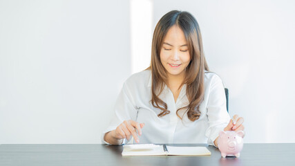 A young woman who puts coins in a piggy bank with accounting, planning and money saving ideas.