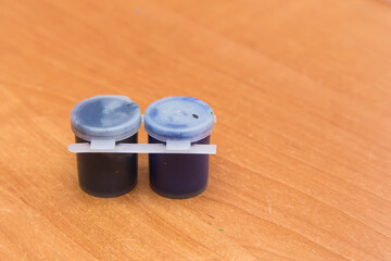 Two closed jars with black and purple gouache for painting. Side view of a half-empty can of...