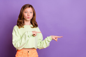 Photo of young girl happy smile pouted lips send air kiss point fingers empty space ad choice isolated over purple color background