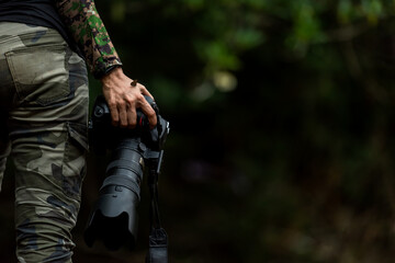 Close up hand and butterfly.  Professional photographer woman holding camera for taking butterfly in the green jungle rain forest nature. Travel and Vacations Concept