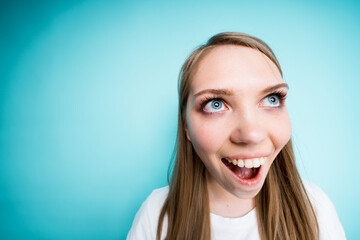 Close-up photo. Happy beautiful girl smiles broadly while standing on a blue background. Fish eye...