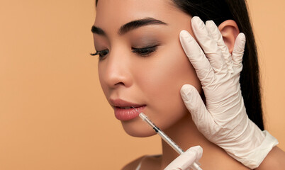 Young Asian woman with clean radiant skin gets botox injections for contour tightening, lip...