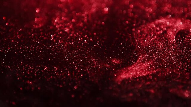 Red glitter background in slow motion. Cinematic red particles on black background