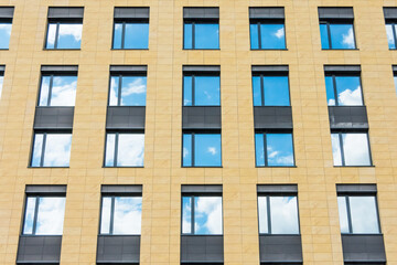 Fototapeta na wymiar Separate windows office building yellow wall with clouds sky mirror.