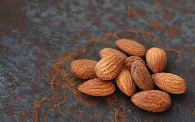 peeled whole nuts almonds on a metallic background