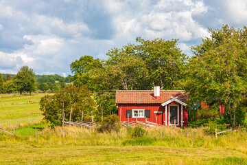 Fototapeta na wymiar Red idyllic cottage with wooden fence