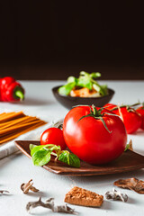 Juicy tomato with pasta and vegetables on bright background. Spaghetti base.