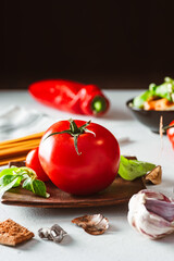 Juicy tomato with pasta and vegetables on bright background. Spaghetti base.