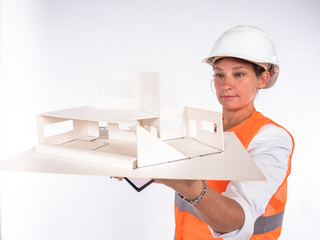 Woman architect is holding a mock house in front of her. Three-dimensional model of house in hands of architect. Woman examines volumetric layout of cottage. Concept - work of architect.  Planner