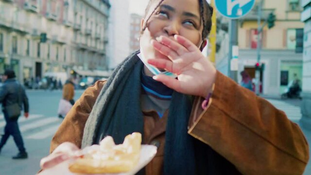 Portrait of young woman eating pastry outdoors, Italy