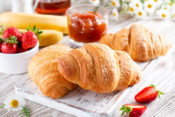 Fresh croissants with jam for breakfast on table. French pastry