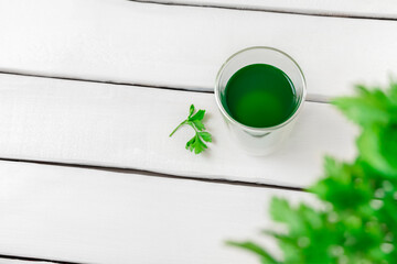 Top view of chlorophyll water in a glass on white wooden table with copy space - obrazy, fototapety, plakaty