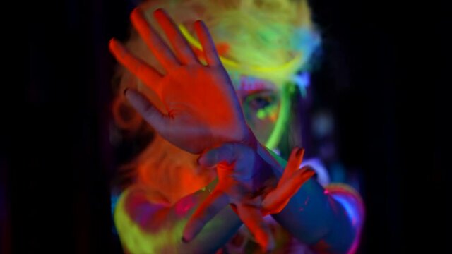 extravagant fluorescent makeup on face and body of young woman, closeup portrait