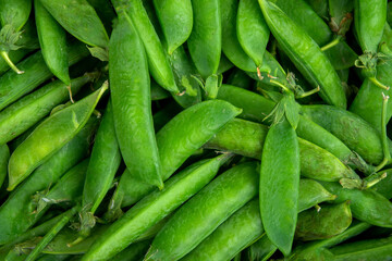 pods of harvested green peas background close-up top view