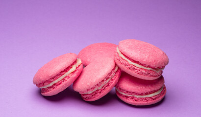 Colorful sweet macarons or macaroons, flavored cookies on purple background.