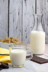 breakfast and snack with milk, chocolate and homemade breads with bottle and elegant glass and sugar on counter and wooden background