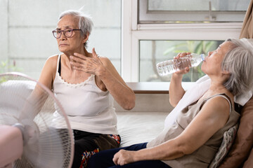 Asian elderly people who are hot and thirsty from high temperature heat waves,drinking water help...
