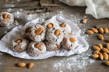 Amaretti, traditional Italian cookies with almonds on baking paper on wooden background background. Selective focus