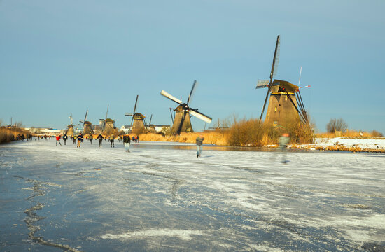 Nederland, Zuid-Holland, Kinderdijk, People Ice Skating Near Windmills