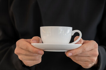 Closeup of professional male barista hand making and holding white cup of coffee. .
