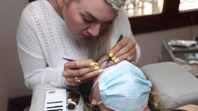 Beautician applying eyelashes on face of woman