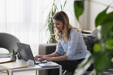 Young beautiful woman working on a computer at home, calculating monthly exspences, mortgage payments, doing home budgeting