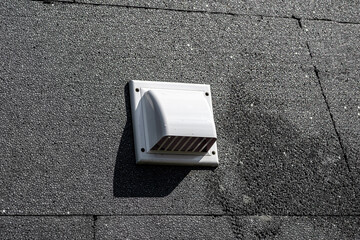 A plastic ventilation grille on the building facade made of black insulating styrofoam.