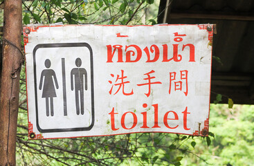 Closeup of old public toilet sign for men and women with translation in three languages (thai,...