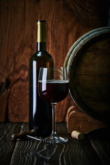 Wine bottle, Wine Cask, wine glass with a corkscrew and a cork stopper shot on rustic textured wooden table.
