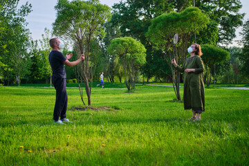 A young man and an adult woman in face medical masks are engaged in sports in nature