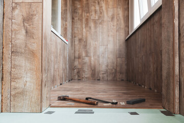 Laying laminate flooring on the loggia. The laminate laying tool lies on top of the installed laminate in the room.