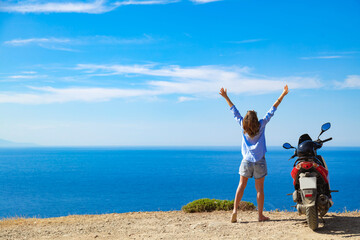 Woman with scooter looking at the distant sea horizon.