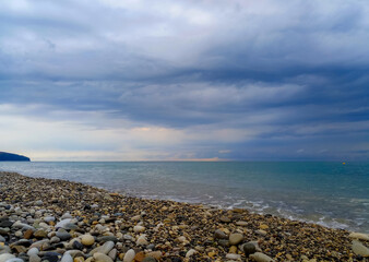 Amazing sea sunset on the pebble beach, the sun, waves, clouds