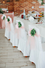Decor of chairs for a festive dinner, using fresh flowers and white fabric. Selective focus.