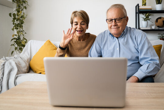 Hispanic Senior Couple Doing Video Call Having Fun With Laptop Computer At Home - Joyful Elderly Lifestyle And Technology Concept - Focus On Faces