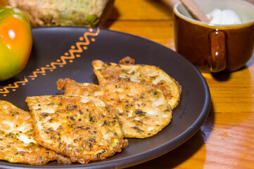 Vegetarian food - celery tuber slices fried in batter in a ceramic plate on a wooden table, close up