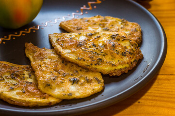 Vegetarian food - celery tuber slices fried in batter in a ceramic plate on a wooden table, close up