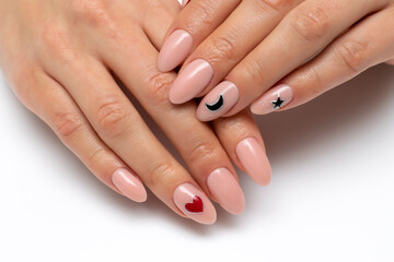 Delicate manicure. Beige, natural manicure with a painted black moon, stars and a red heart on long oval nails close-up on a white background.
