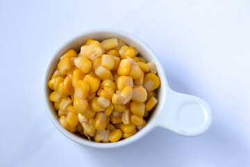 Corn boiled in a white ceramic cup on a white background.
