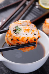  sushi roll holding by sticks. sushi rolls served at grey  tray. flat lay. close up