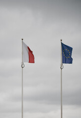 Real world photo of Polish and European Union flags. Polish and EU flag on pole. Government relationship concept.