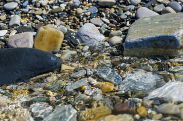 Fototapeta premium pebble stones on the sea beach, the rolling waves of the sea with foam