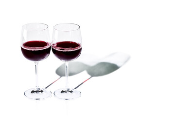 A couple of glasses with red wine on a white background. Minimal still life with a hard shadow.