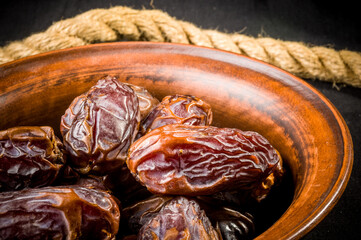 Big luxury dried date fruit in bowls on the dark surface, kurma ramadan kareem concept, close up.