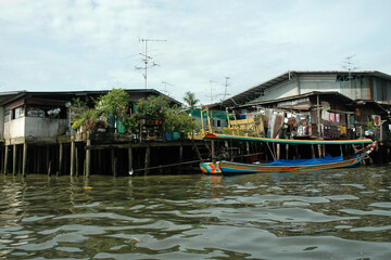 Fototapeta na wymiar Stilt slum housing in Bangkok with boat used for touring in foreground